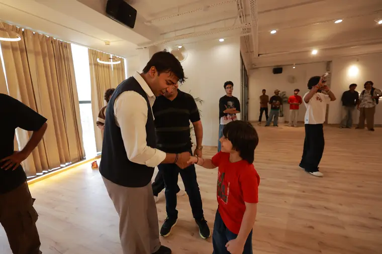 An instructor welcoming a young dancer
